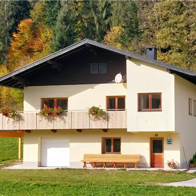 Ein modernes Haus in ländlicher Umgebung mit einem gepflegten Garten. Die Fassade ist freundlich gestaltet und mit Blumen dekoriert.