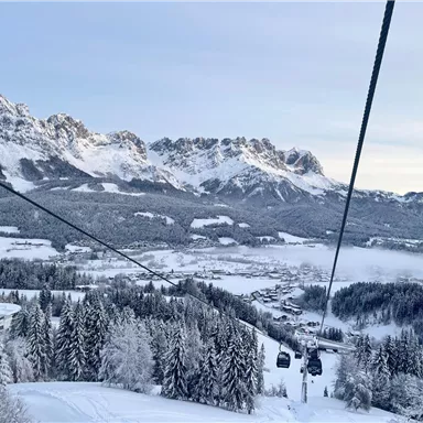 A beautiful winter landscape with snow-covered mountains and fir trees. A cable car crosses the landscape.