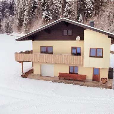 A cozy house in a snowy landscape. Surrounded by trees and fresh snow, it creates an inviting atmosphere.