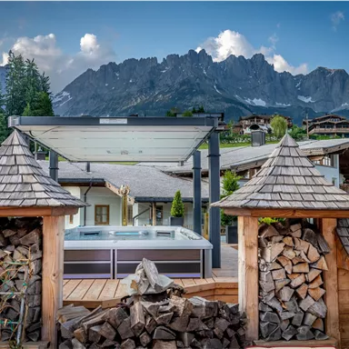 Eine schöne Aussicht auf die Berge mit einem Whirlpool im Vordergrund. Umgeben von Holzstapeln und traditioneller Architektur.