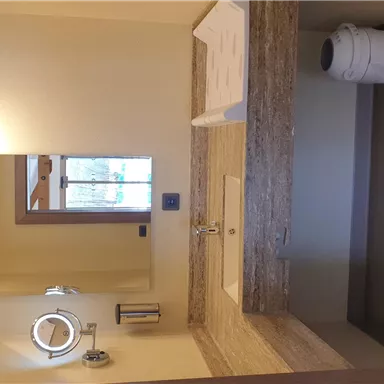 A modern bathroom with an elegant sink countertop. In the background, a mirror and a window are visible.