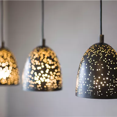 Drei dekorative Pendelleuchten mit einem einzigartigen Design und warmem Licht. Sie schaffen eine gemütliche und einladende Atmosphäre.