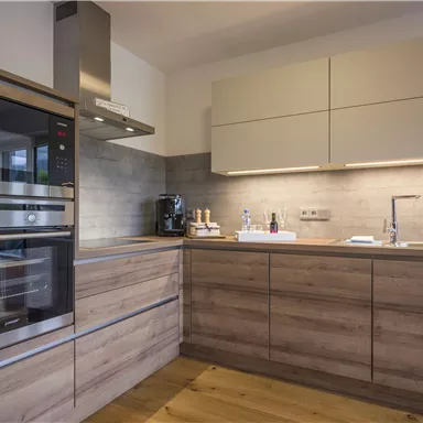 Moderne Küche mit holzfarbenen Möbeln und hochwertigen Geräten. Gut ausgestattet mit einem eleganten Design und viel Stauraum.