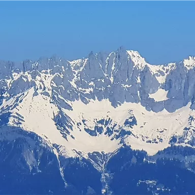 A majestic mountain panorama with snow-covered peaks. The clear blue sky enhances the impressive landscape.