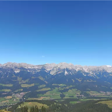 Eine beeindruckende Berglandschaft mit majestätischen Gipfeln und grünen Tälern. Der klare, blaue Himmel verstärkt die Schönheit der Natur.