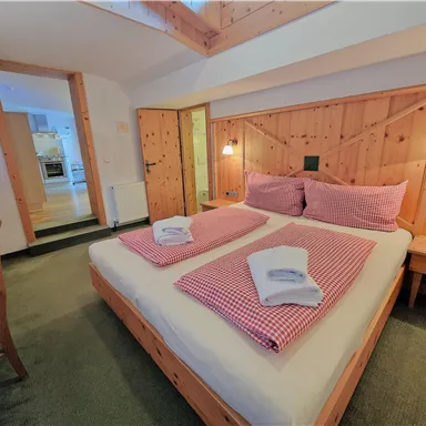 Ein gemütliches Schlafzimmer mit einem großen Bett und Holzverkleidung. Der Raum ist hell und einladend, mit einem Tisch und Stühlen.