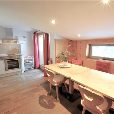 Eine moderne Küche mit einem großen Essbereich. Helle Farben und gemütliche Möbel schaffen eine einladende Atmosphäre.