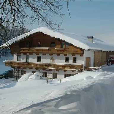 Ein malerisches Haus im Winter, umgeben von schneebedeckter Landschaft. Der Himmel ist klar und die Atmosphäre ist ruhig und friedlich.