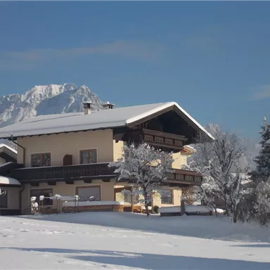 A beautiful house in a snow-covered landscape. Snow-covered mountains are visible in the background.