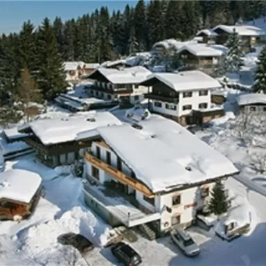 A picturesque mountain landscape with snow-covered houses and trees. The area is calm and idyllic.