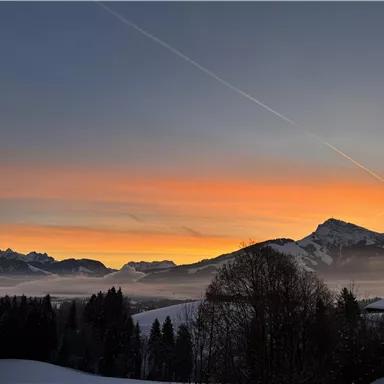 A beautiful sunrise over snow-covered mountains. The color palette ranges from orange to blue in the sky.