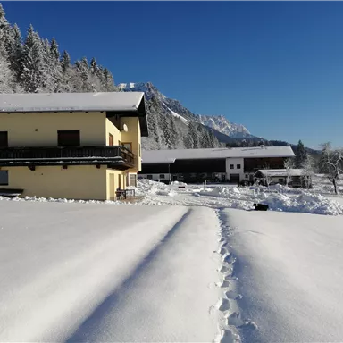 A cozy house in a snowy landscape. The sky is clear and the surroundings are covered with fresh snow.
