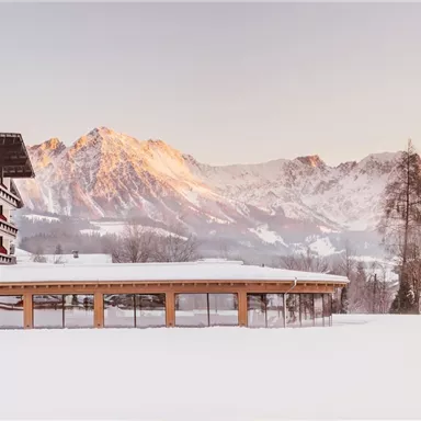 A picturesque winter panorama with snow-covered mountains and a charming hotel. The landscape radiates peace and beauty.