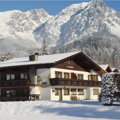 A charming house in the snow, surrounded by majestic mountains. The clear blue sky gives the winter landscape a special beauty.