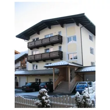 Ein mehrstöckiges Wohnhaus mit hellen Wänden und Balkonen. Es ist mit Schnee bedeckt und befindet sich in einer ruhigen Umgebung.