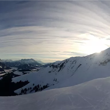 Eine beeindruckende Winterlandschaft mit schneebedeckten Bergen und einer tiefblauen Himmel. Die Sonne scheint sanft über die Alpen.