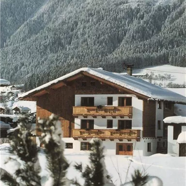 A charming chalet in the snow, surrounded by snow-covered mountains. The cold winter landscape conveys a cozy atmosphere.