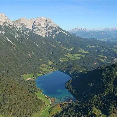 A picturesque landscape with mountains and a clear lake in the middle. Surrounded by green meadows and forests, the beauty of nature unfolds.