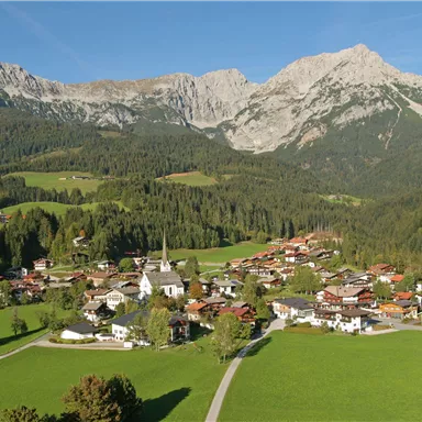 A picturesque alpine landscape with a small village in the valley. Majestic mountains rise in the background, and lush meadows stretch out.