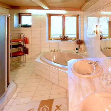 A modern bathroom with a freestanding bathtub and a shower. Bright tiles and windows create a friendly atmosphere.