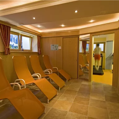 Ein entspannender Wellnessbereich mit Liegen und großen Fenstern. Der Raum ist hell und einladend, ideal für Erholung.