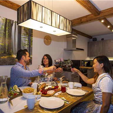 A cozy dinner with friends in a modern kitchen. The table decoration includes delicious food and drinks, while everyone toasts.