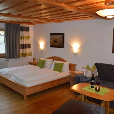 Ein gemütliches Schlafzimmer mit einem großen Bett und einer Sitzecke. Der Raum hat Holzdetails und angenehme Beleuchtung.