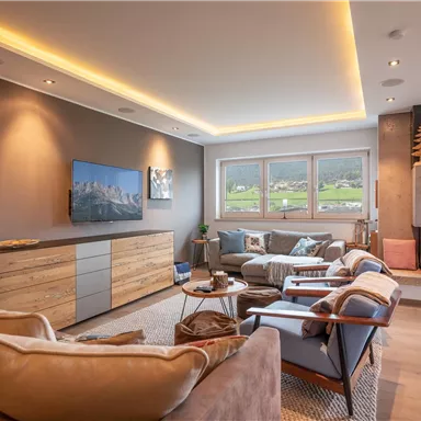 Ein modernes Wohnzimmer mit gemütlichem Kamin und eleganter Einrichtung. Große Fenster bieten einen Blick auf die umliegende Landschaft.