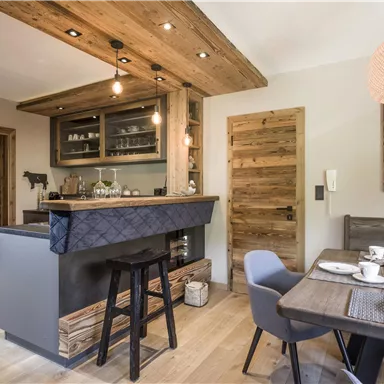 Eine moderne Küche mit Holzelementen und einem minimalistischen Thekenbereich. Der Essbereich ist elegant gedeckt und schafft eine gemütliche Atmosphäre.