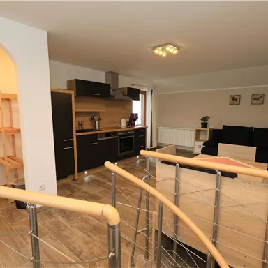 Ein modernes Wohnzimmer mit einer offenen Küche und einem gemütlichen Sofa. Der Raum ist hell und einladend, mit praktischen Möbeln und einer angenehmen Atmosphäre.