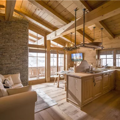 Ein gemütliches Holzinterieur mit einer modernen Küche und einem bequemen Sofa. Große Fenster lassen viel Licht herein und bieten einen Blick auf die Umgebung.