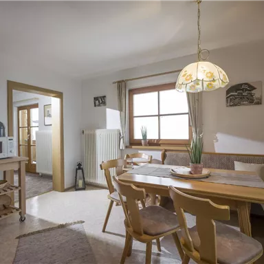 A bright and cozy kitchen with a dining table and chairs. The walls are painted in neutral tones, with windows that let in natural light.
