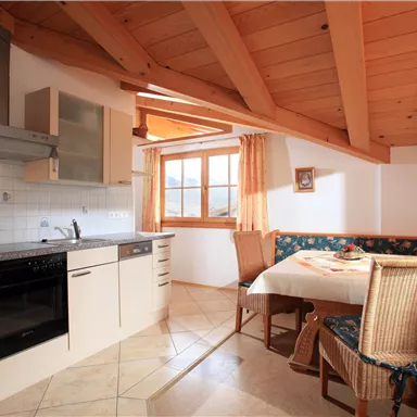 A cozy kitchen with wooden ceilings and modern design. A dining area with a table and bench invites you to linger.