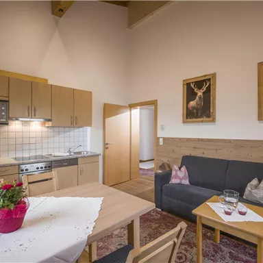 Eine gemütliche Wohnung mit einer modernen Küche und einem Wohnbereich. Der Tisch ist schön gedeckt, und an der Wand hängen Bilder.