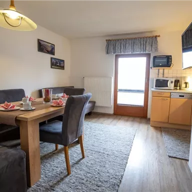 Eine gemütliche Wohnung mit einem Esstisch und einem Küchenbereich. Die Räume sind hell und einladend eingerichtet.