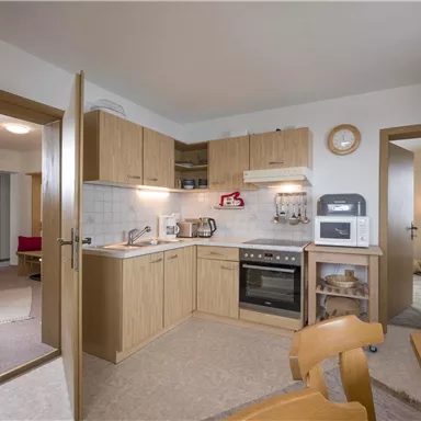 A cozy kitchen with wooden cabinets and modern appliances. The room is bright and inviting, with a wooden dining area.