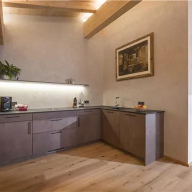 A modern kitchen with wooden shelves and a large window. The space has a warm, inviting character.