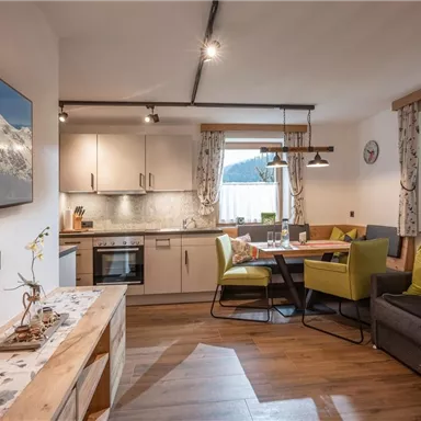 A cozy kitchen with modern appliances and a dining table. Bright colors and wooden details create an inviting atmosphere.