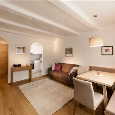 A cozy living room with a dining table, a sofa, and a television. The rooms are bright and furnished in a modern style.