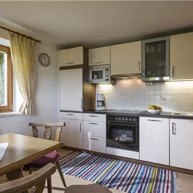 Eine einladende Küche mit modernen Geräten und einer gemütlichen Essplatz. Helle Fenster sorgen für angenehmes Licht und eine freundliche Atmosphäre.