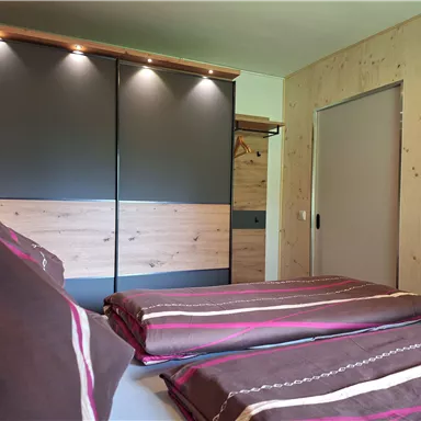 A modern bedroom with two beds and stylish wood and gray tones. The room is bright and inviting, perfect for relaxation.