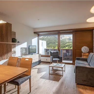 Modern apartment with a cozy living room and a beautiful view of the mountains. The space is bright and inviting, featuring a dining area and elegant furnishings.