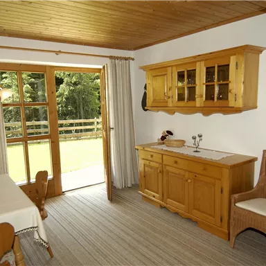 Ein gemütlicher Essbereich mit Holzmöbeln und großen Fenstern. Der Raum ist hell und freundlich mit Blick auf die Natur draußen.