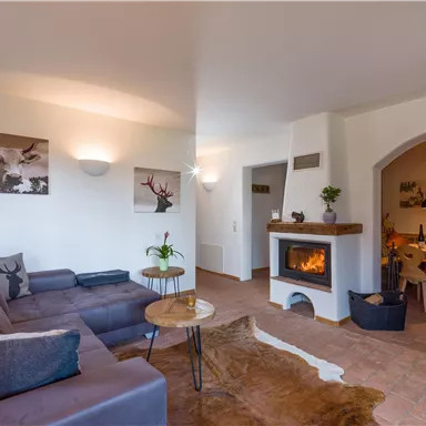 A cozy living room with a modern couch and a fireplace. The walls are light and decorated with decorative pictures.