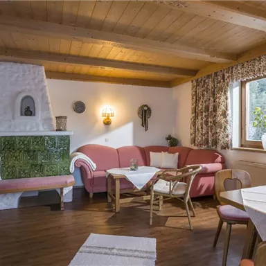 A cozy living space with a red couch and a wooden table. The warm wooden ceilings and the windows let in a lot of light.