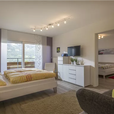 A modern bedroom with a double bed and a television. Large windows provide a beautiful view and plenty of natural light.