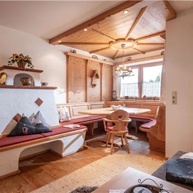 A cozy dining area in alpine style with a wooden table and a bench. The room has a warm atmosphere with plenty of natural light.