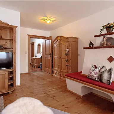 A cozy living room with wooden furniture and a fireplace. The room is bright and invitingly designed.