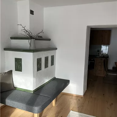 Ein moderner Wohnraum mit einem Kamin und einer gemütlichen Bank. Die Wände sind in Weiß gehalten und der Boden ist aus Holz.