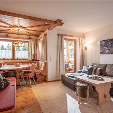 A cozy living room with a wooden ceiling and an inviting seating area. A dining area with a table and chairs complements the space.